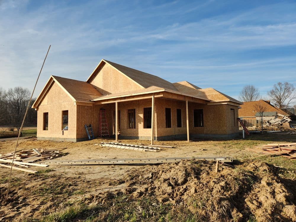 Newly constructed home with wooden framing and a clear blue sky in the background.
