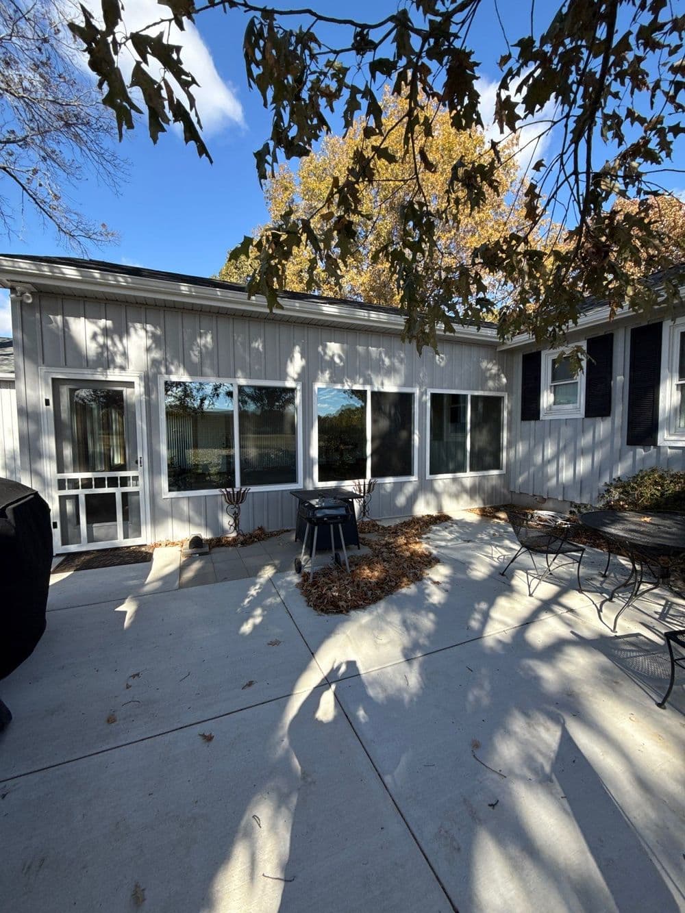 Outdoor patio featuring a seasonal view, surrounded by trees and sunlight. Ideal for gatherings.