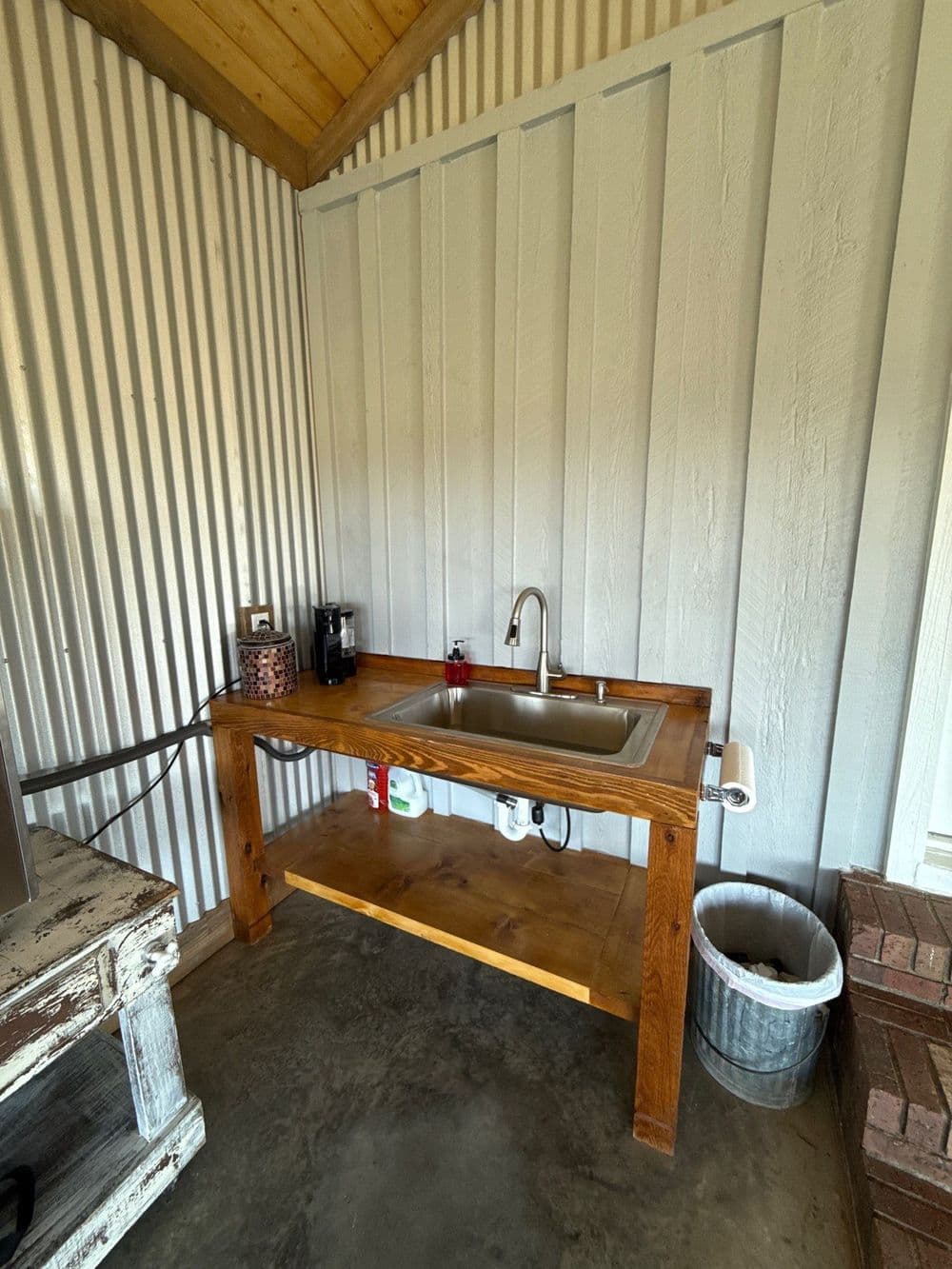 Rustic wooden sink station with metal faucet, countertop, and storage underneath, in cozy cabin setting.